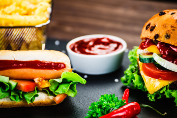 Tasty burger and hot dog on black stone