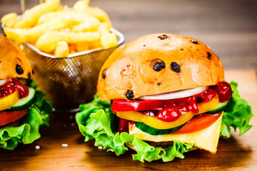 Tasty burgers with chips served on cutting board