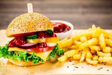 Tasty burger with chips served on cutting board