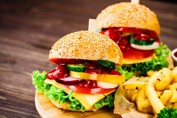 Tasty burgers with chips served on cutting board