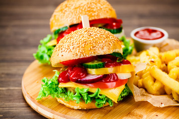 Tasty burgers with chips served on cutting board