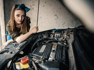 Fototapeta na wymiar A beautiful girl repairs and maintains a car in the garage. Women in Men's Professions
