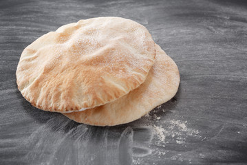 Pita bread on a black table sprinkled with flour
