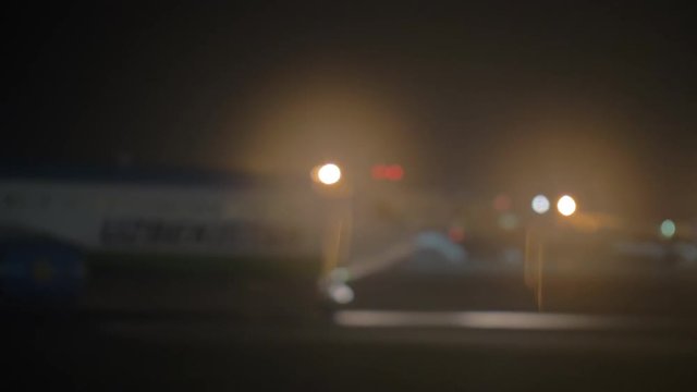 Slow motion defocused shot of airplane arriving and driving to airport terminal at night