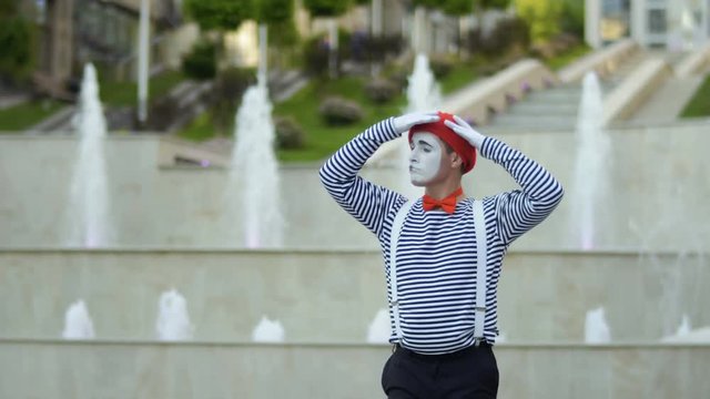 Funny mime in red beret preparing to performance at fountains background