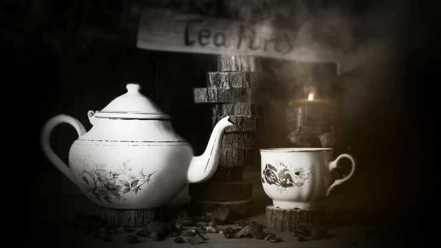 4K Cinemagraph - Cup of Tea and Teapot On Wooden Table With Arrow Sign, Smoke ,Candle Flame and Light in The Background. Tea Party Concept
