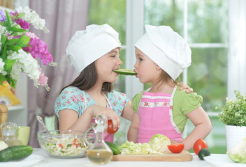 Two adorable little girls in aprons having fun