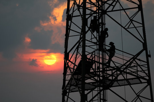 Workers are climbing to repair the telecommunication tower,Red sky sunset background