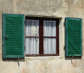 Okno z firanką i drewnainymi, ładnymi, w stylu vintage, zielonymi okiennicami z drewna, mur domu - obrazy, fototapety, plakaty