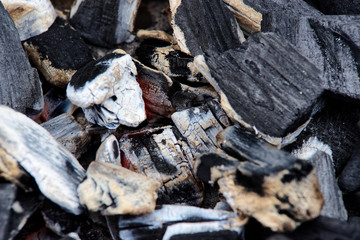 Close-up top view of hot charcoal glowing in a grill pit. Abstract charcoal background