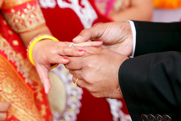 Indian groom putting ring on indian bride
