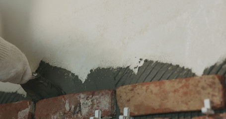 worker remove excessive concrete glue to wall before applying brick tile