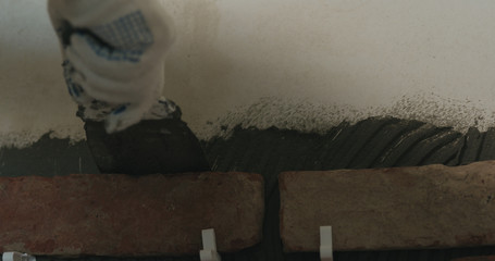 worker remove excessive concrete glue to wall before applying brick tile