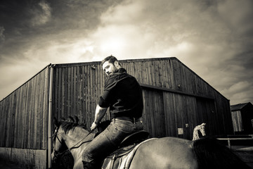 Handsome cowboy, horse rider on saddle, horseback looks over his shoulder