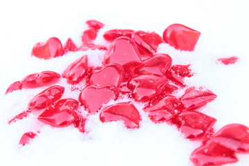 Beautiful red voluminous transparent hearts made of fiberglass in natural cold snow. Close-up. Background. Texture.