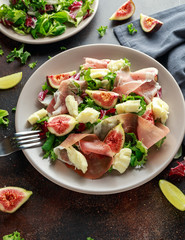 Fresh figs salad with prosciutto, green mix and cheese in a plate