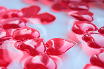 Beautiful red decorative hearts made of fiberglass in water. Close-up. Texture. Background.