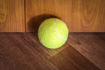 A tennis ball lies in the corner of the room.