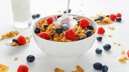 Healthy Morning Breakfast honey Corn flakes with fresh fruits of Raspberry, blueberries and pouring...