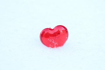 Fototapeta premium Red volumetric heart made of fiberglass in snow. Close-up. Background.