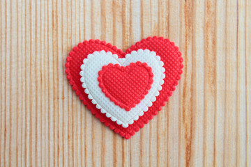 A beautiful red soft heart made of cloth on a light new board. Close-up. Background.