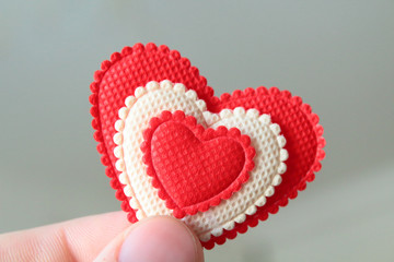 A beautiful red soft heart made of cloth in a man's hand. Close-up. Background.
