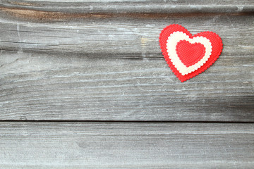 A red soft beautiful heart pasted onto an old board. Background.