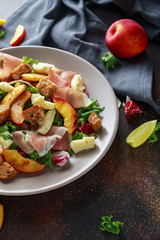 Fresh grilled peach salad with green mix, cheese, prosciutto and crouton
