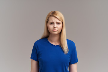 Obraz premium Sad pretty girl feeling upset while spending time at home alone. Beautiful young female with blond hairs staring at camera