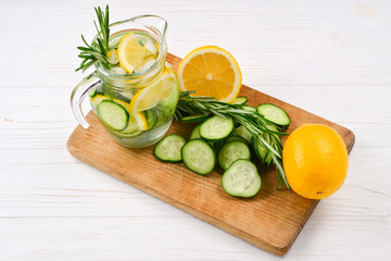 Cold and refreshing detox water with lemon, cucumber, rosemary and ice in glass jar. Copyspace. Banner