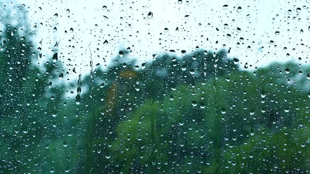 The rain drips on the window glass. Drops of rain flow down the glass. Outside the window, the weather is bad. Autumn season of rains and downpours.