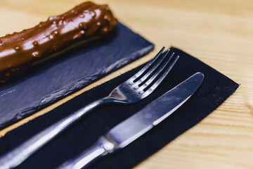 delicious chocolate eclair with a fork and a knife