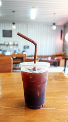 Iced americano on a wooden table in a cafe.