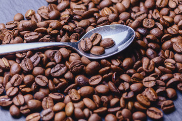 spoon on coffee beans on black stone background