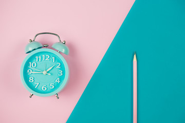 Alarm clock on pink and green background.