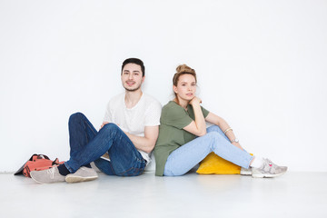 Indoor shot of charming young European woman and man students relaxing at home after college,...