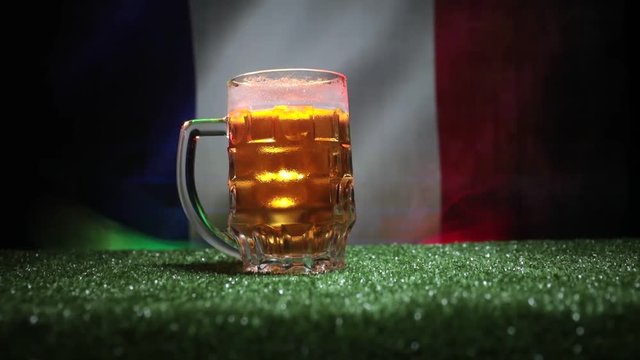 Creative concept. Pint of fresh beer on grass with blurred flag of France on background or Glass of lager beer ready for drink. Copy space. Selective focus