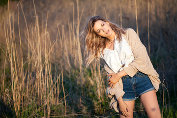 Cute charming girl in summer in the field. Young woman is happy and feels free outdoors