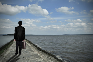 Businessman walking on the pier over sea 