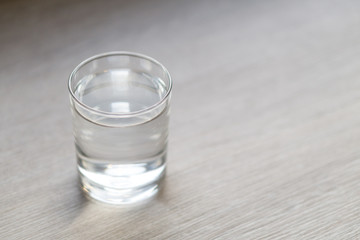 Glass of water on wood table with light in the morning, healthy care concept, selective focus