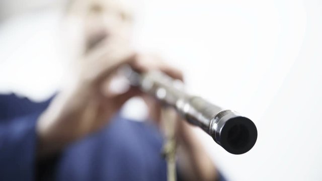 End of bamboo flute while person playing low angle view 4K. Static low angle close up on flute in focus with person in background tapping on holes out of focus. Enjoying music.