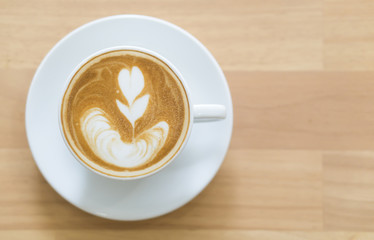 Closeup top view glass of latte art coffee tulip shape on wood background with vintage color, selective focus