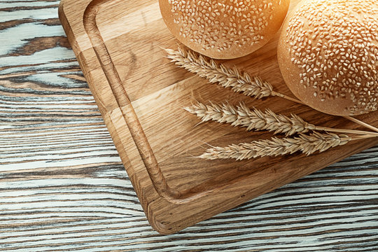Chopping board bread wheat ears on wooden surface
