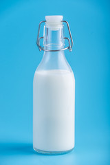 Glass bottle with fresh milk on blue background. Colorful minimalism. Concept of healthy dairy products with calcium