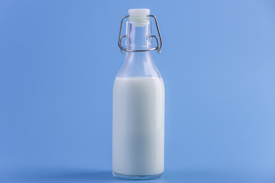 Glass bottle with fresh milk on blue background. Colorful minimalism. Concept of healthy dairy products with calcium