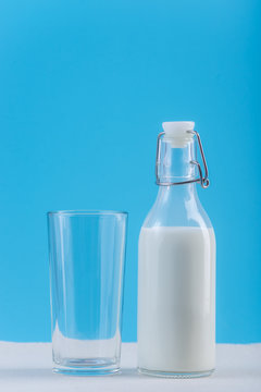 Bottle of fresh milk and glass on blue background. Colorful minimalism. Concept of healthy dairy products with calcium