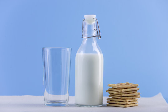 Glass bottle of fresh milk and cookies on blue background. Colorful minimalism. Concept of healthy dairy products