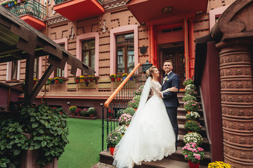 Wedding in a beautiful location. Bride and groom holding hands and going up the stairs. Elegant wedding dress with a long train
