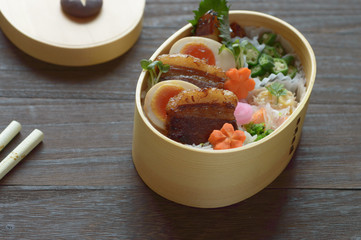 a delicious looking bento consists of braised pork belly, boiled eggs, steamed rice and the assortment of vegetables
