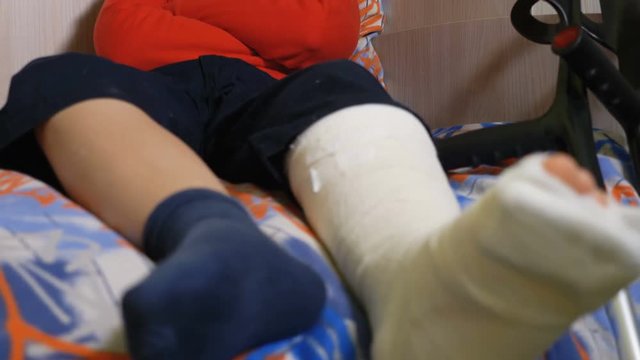 sad and angry boy with broken leg,lying on bed